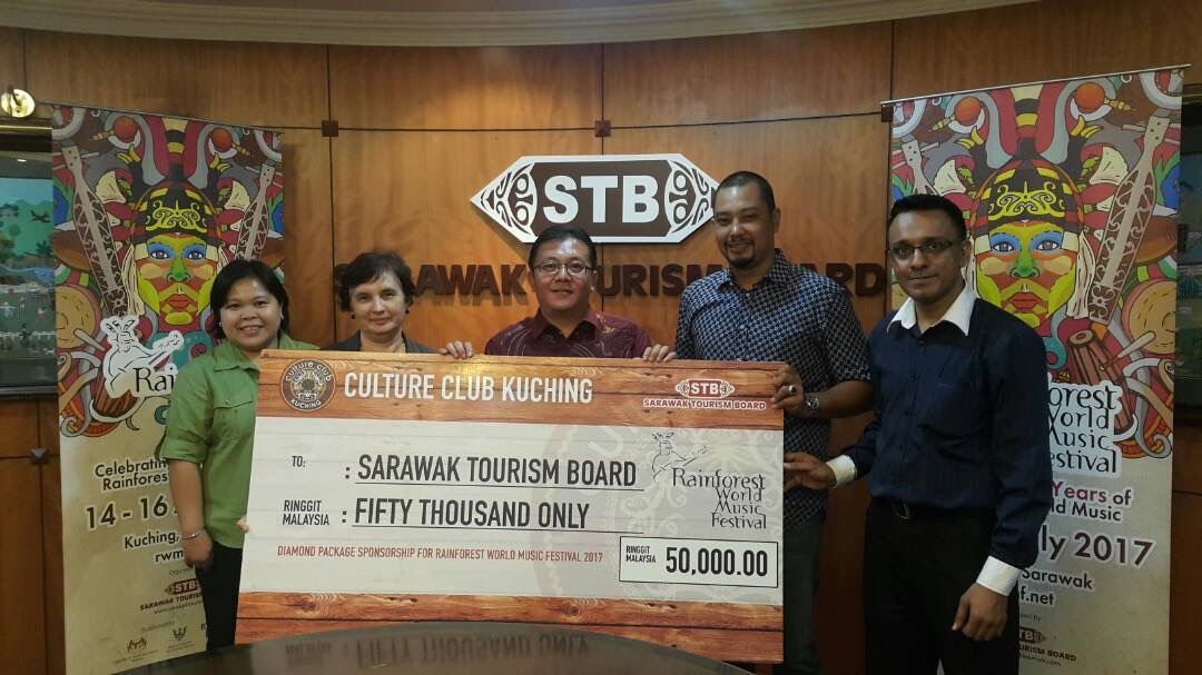 Picture shows Dato Sri Ho (centre) presenting the mock cheque to the representative of the Sarawak Tourism Board, organisers of the Rainforest World Music Festival.
