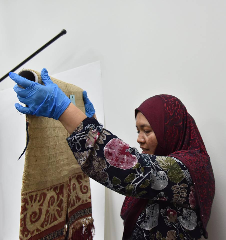 Sarawak museum officer Puan Rahmah preparing a 100 year old Kenyah jacket for the exhibition.