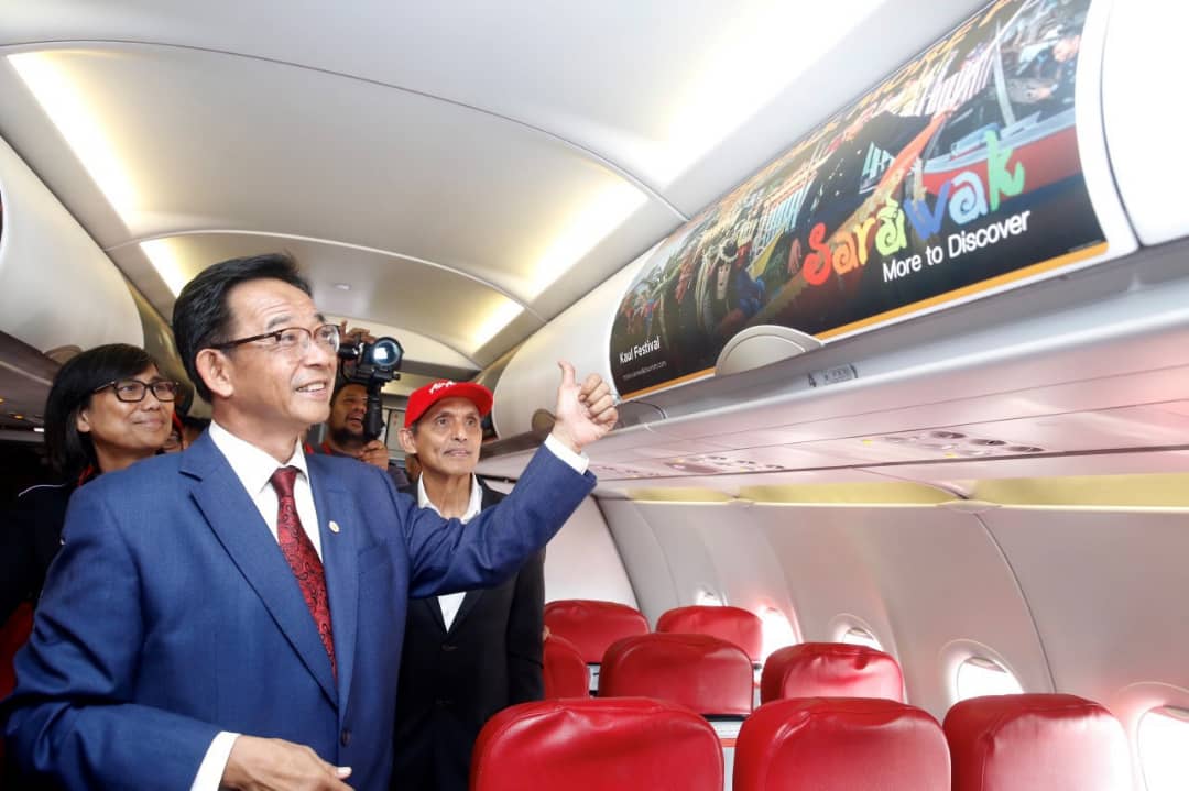 Photo shows Datuk Karim Rahman Hamzah giving a thumbs up at one of AirAsia overhead compartment advertisement panel witnessed by Sharzede Datu Haji Salleh Askor and Dato Aziz Bakar.